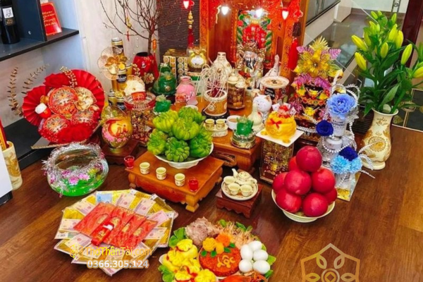 Mâm cúng Thần Tài bày hoa tươi, ngũ quả, xôi và lễ mặn trên sàn gỗ