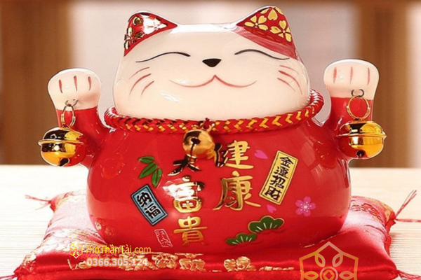 Mèo Thần Tài sứ đỏ hai tay cầm chuông vàng, thân in chữ Hán