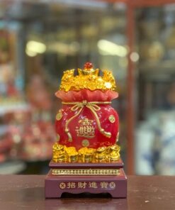 Túi Tụ Bảo bằng sứ đỏ, miệng túi đắp đầy thỏi vàng, đế khắc chữ Chiêu Tài Tiến Bảo